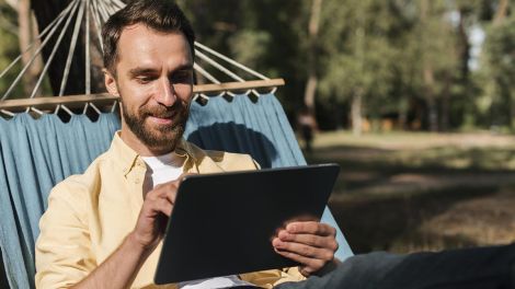 A man relaxing in a hammock using a tablet to take advantage of the free guest Wi-Fi at Yarrawonga Riverlands Tourist Park